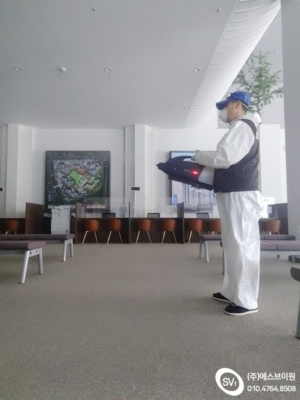 방역복을 갖춘 작업자가 로비를 분무 소독하는 모습
